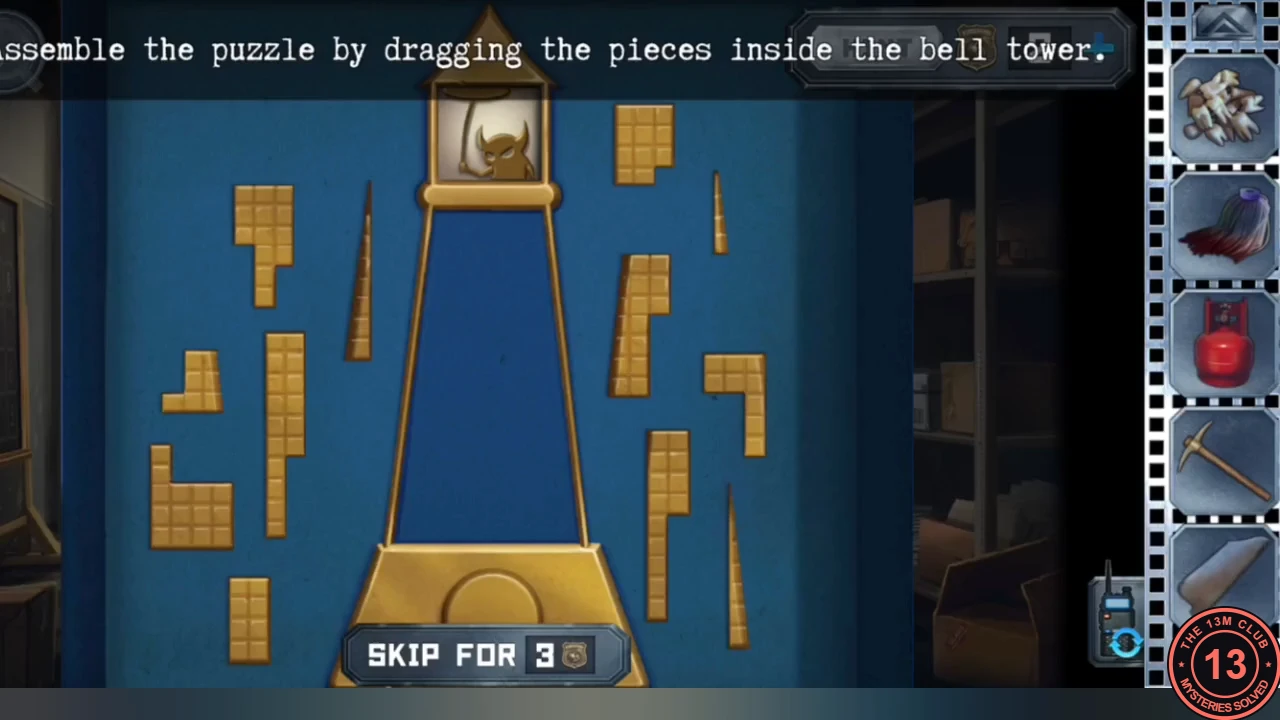 Blue box opened on the office desk: an empty gold bell-tower outline in the middle with loose gold block pieces and thin spikes scattered around it, and the instruction to drag the pieces inside the bell tower.