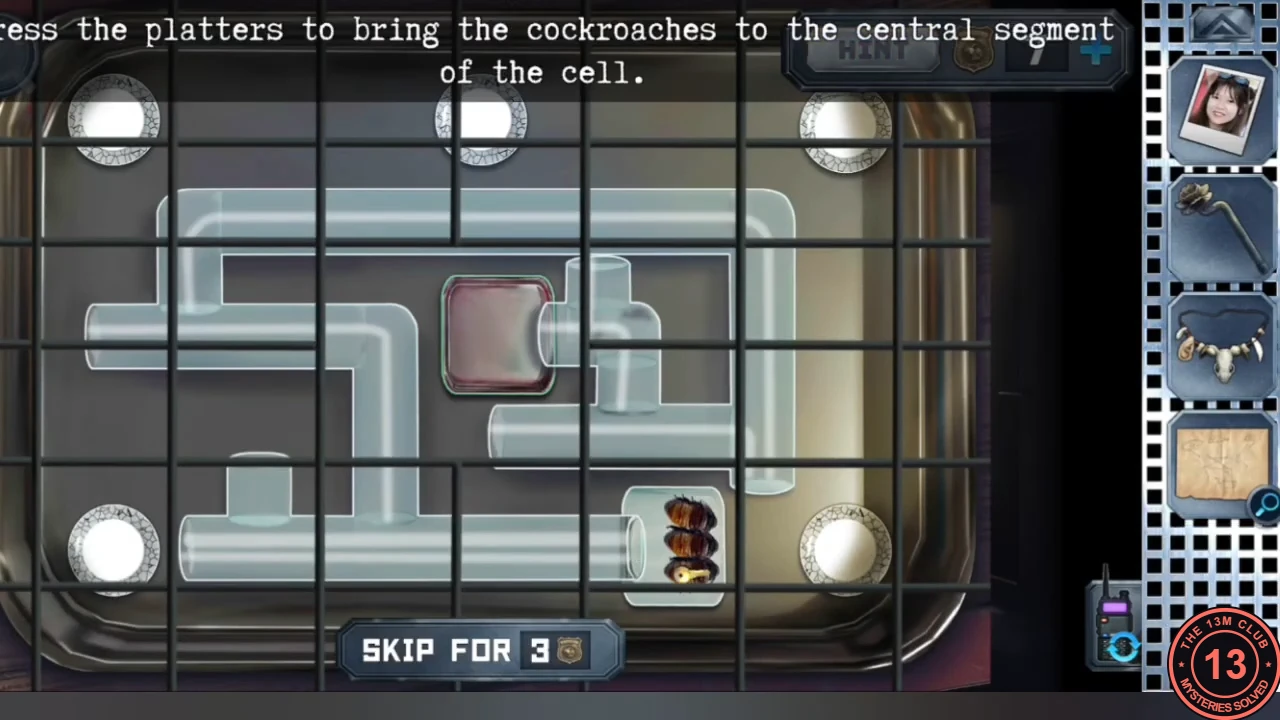 View through the bars of the cockroach cage: glass tubes forming a maze on a tray, empty white plates in the corners and at the top, a red central segment, and a cockroach with the key in a side compartment.