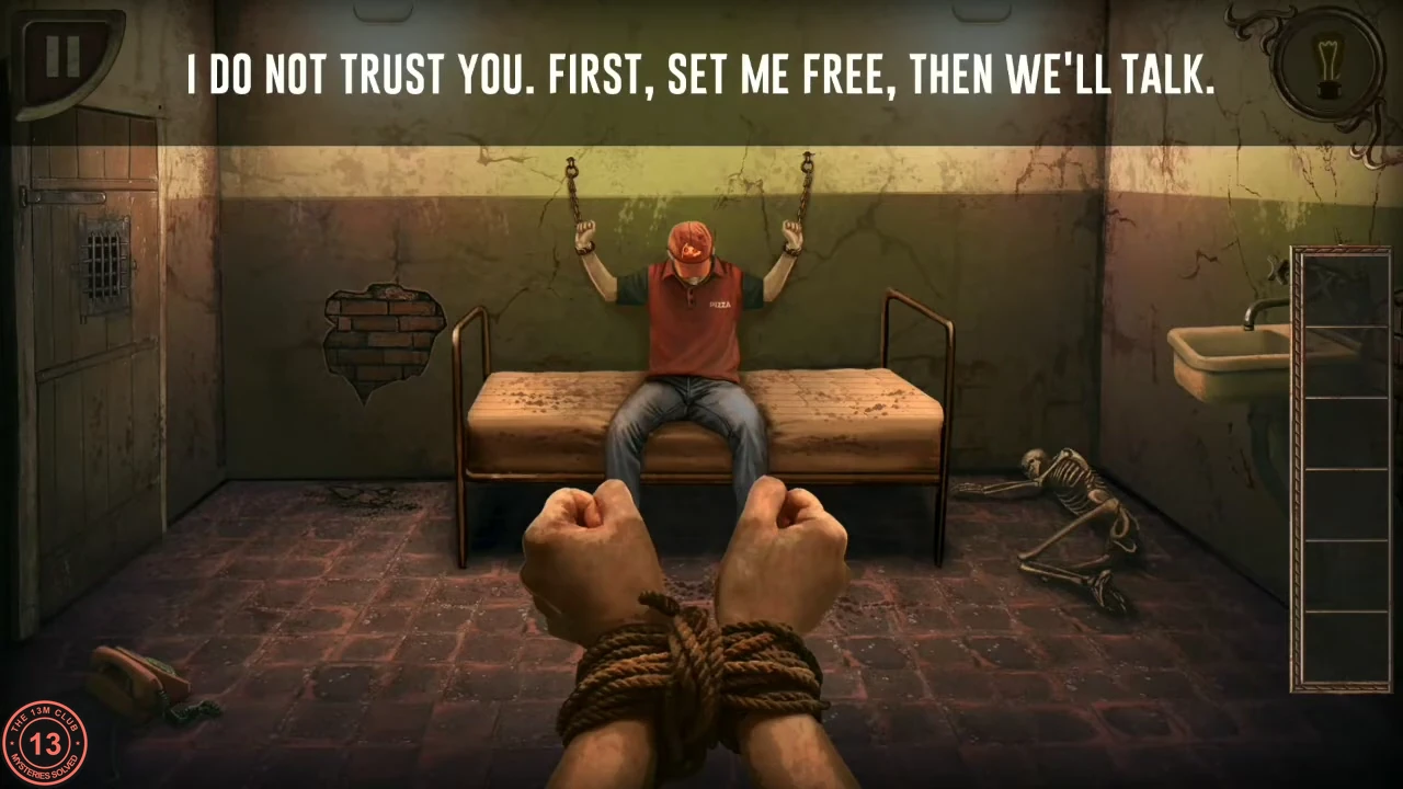 A cell seen from the tied-up player's view: the prisoner in a red cap chained above a bed, a sink on the right and a phone on the floor.