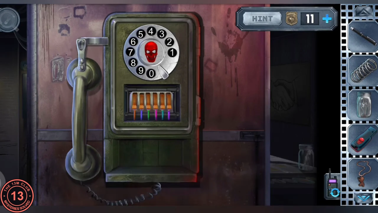 Corridor wall telephone with a rotary dial around a red skull, the handset on the left and the orange terminal block with coloured wires fitted in the box below the dial