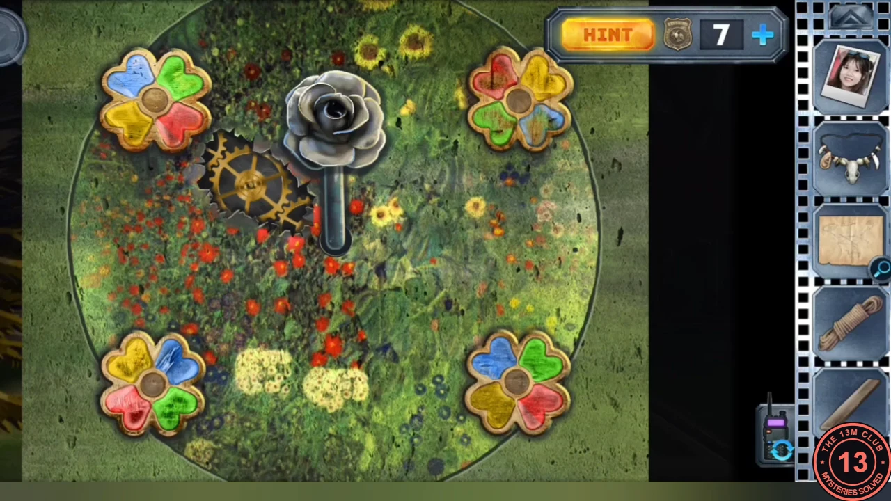 Flower-lever mechanism on the forest floor with four four-petal flowers in red, yellow, green and blue, the golden gear and the metal rose lever in the centre