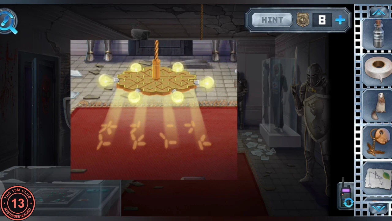 Museum chandelier close-up: its lit bulbs cast four golden glyph shapes in a row onto the red carpet
