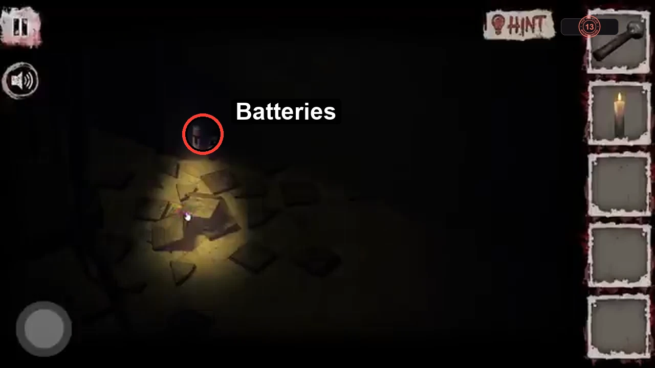 Dark floor close-up with the batteries circled at the far edge of the broken tiles