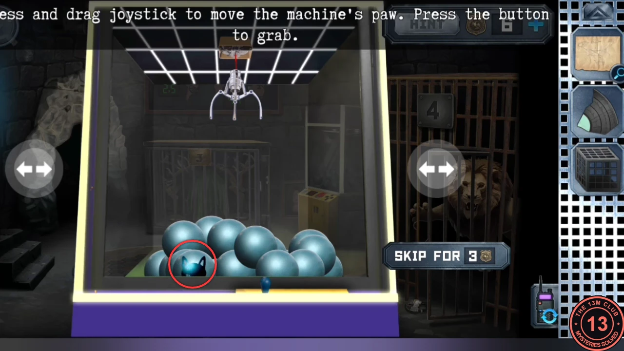 Inside the claw machine: a pile of blue balls with one ball showing a black cat face at the front left, circled in red