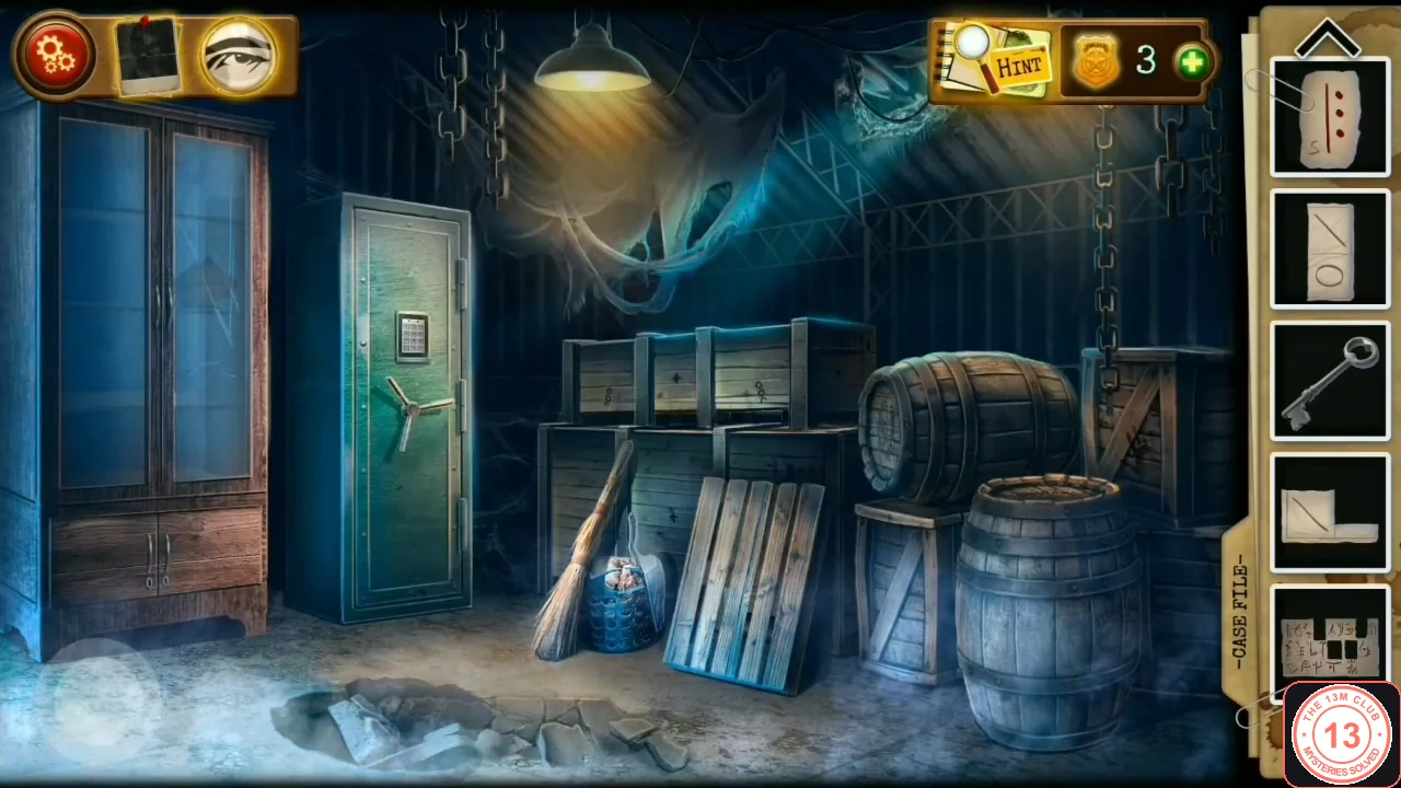 Warehouse with a tall glass cabinet on the left, a big green safe with a keypad, stacked crates, a broom, pallets and barrels