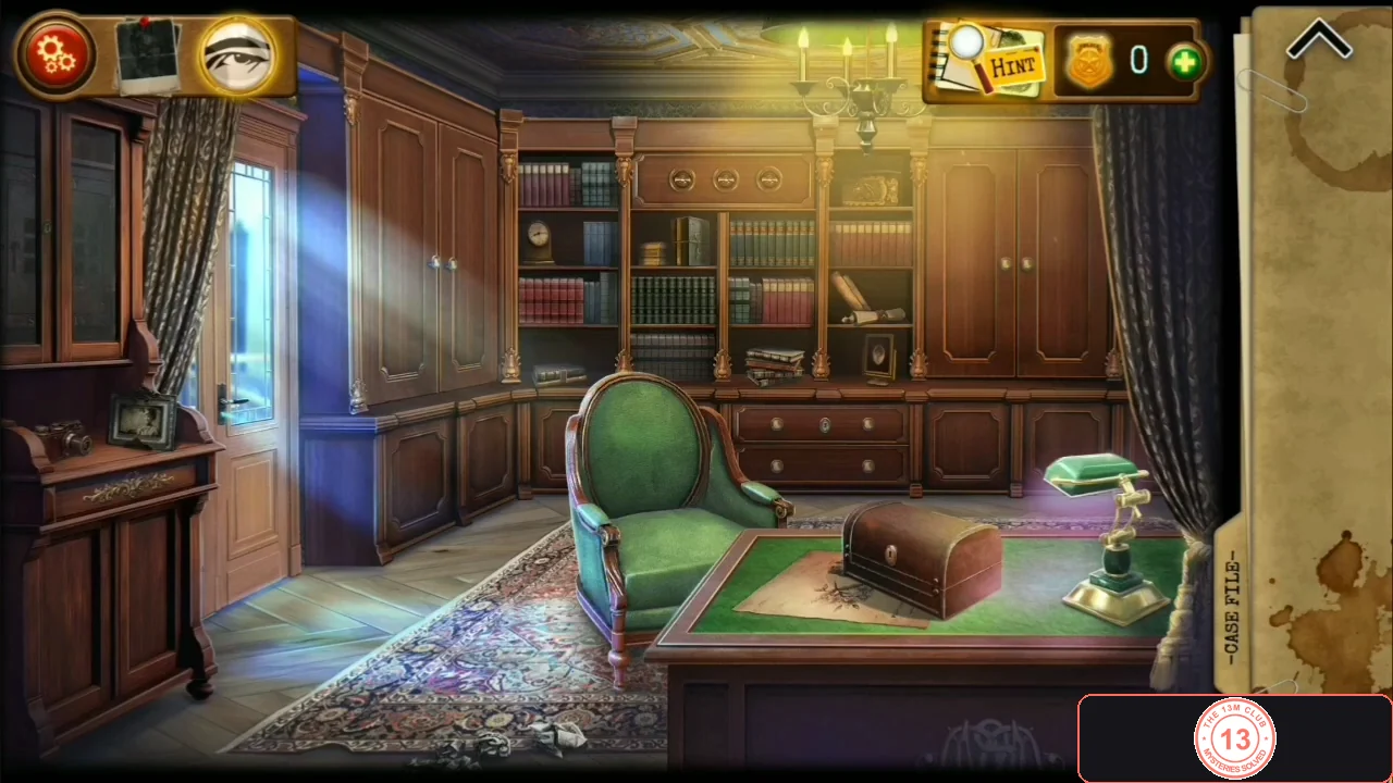 Wood-panelled study with bookcases, a green armchair, a desk with a wooden box and a green lamp, a dark sideboard on the left wall and a door at the left